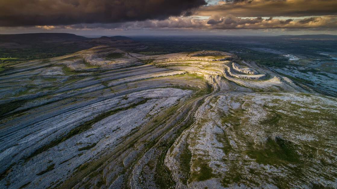 Panoramic view of the Cliffs of Moher, overlooking the rugged coastline of The Burren, with the ocean stretching into the horizon.