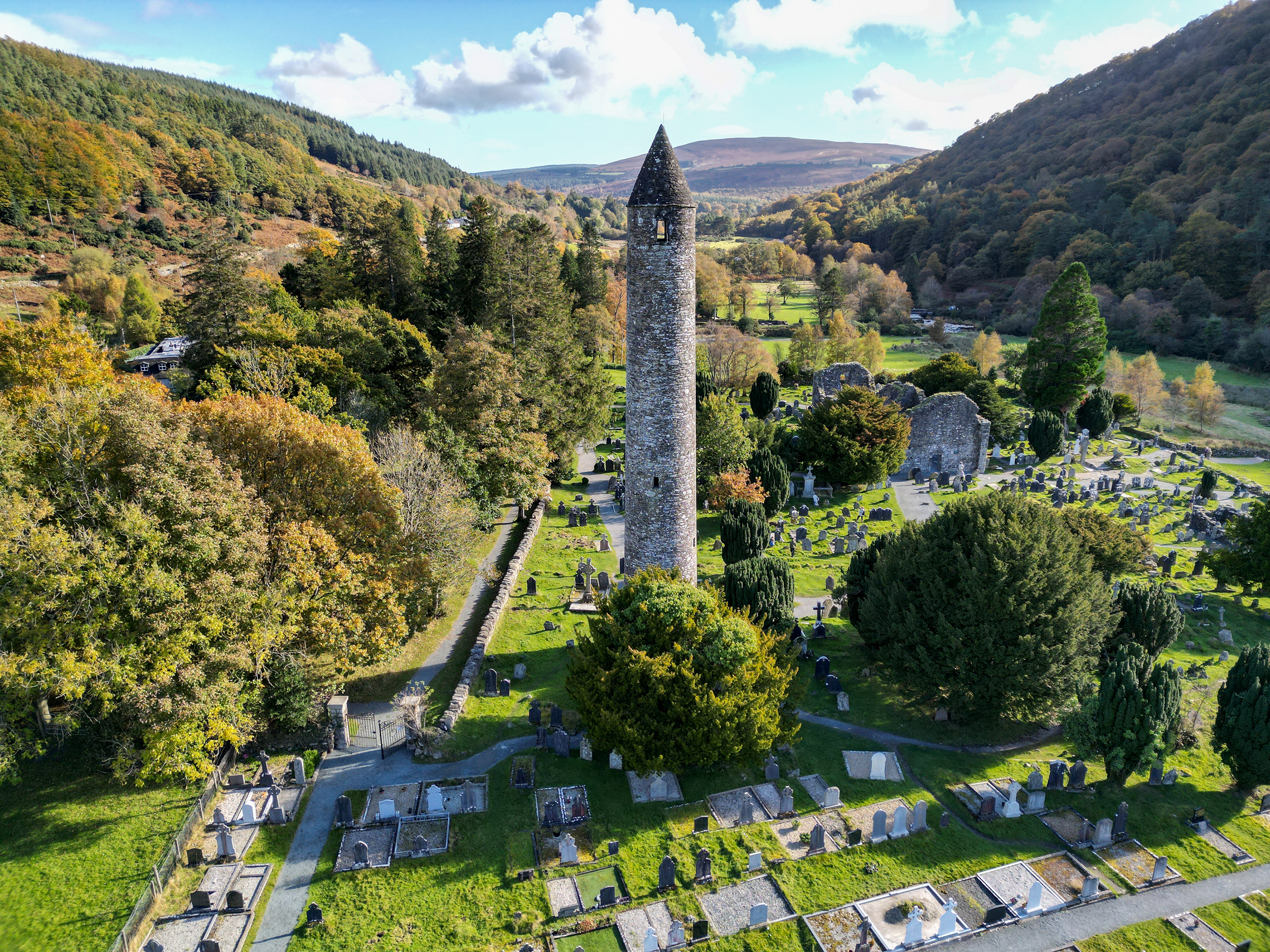 View of the tranquil lakes and lush greenery in Glendalough, Wicklow, surrounded by misty mountains.
